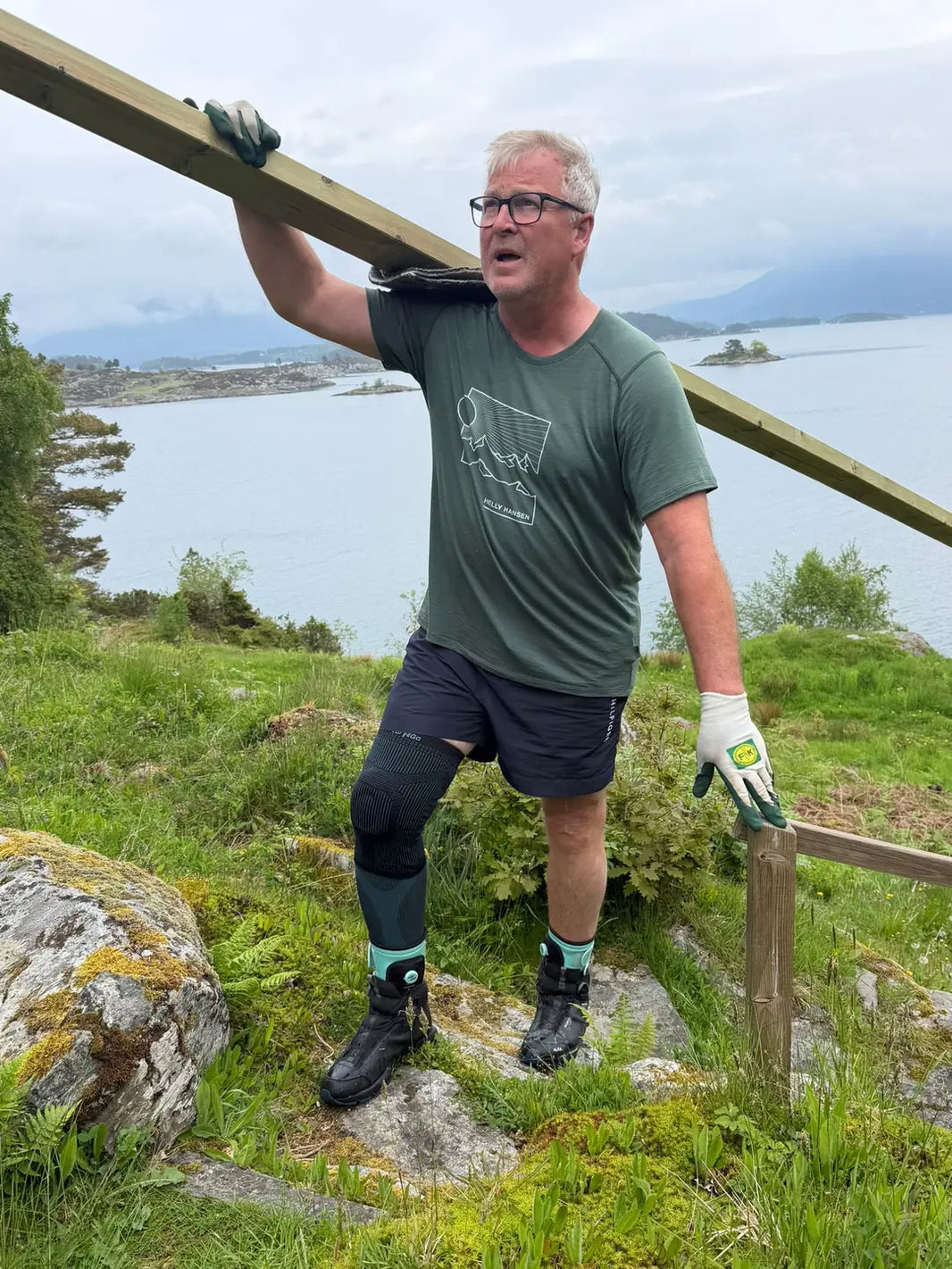 Arnt Ole Ingebretsen bär en trädstam på axeln i oländig terräng på Tjørnøy i Ryfylke, med Wear'N'Go Ankle Trainer på fötterna