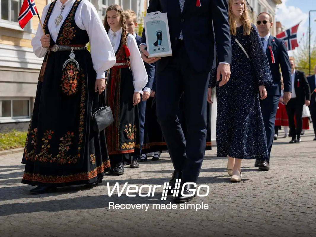 Familj i folkdräkt och festkläder väntar på barnetåget en solig 17 maj-morgon i Norge.