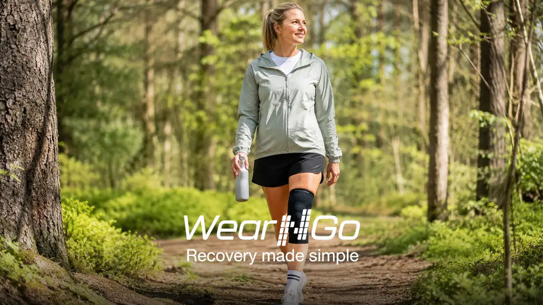 Norsk kvinna i 30-40-årsåldern promenerar i skogen med Wear'N'Go knästöd på höger knä, visar förebyggande användning i en aktiv vardag i maj